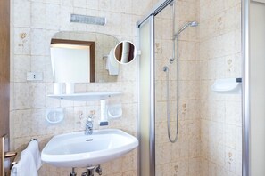 A bathroom with a sink, mirror, and shower. - Hotel Tirolerhof (Brunico)