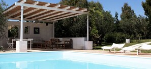 A pool area with a covered seating area, lounge chairs, and a table. - Giardino Giamperduto Hotel (Bernalda)
