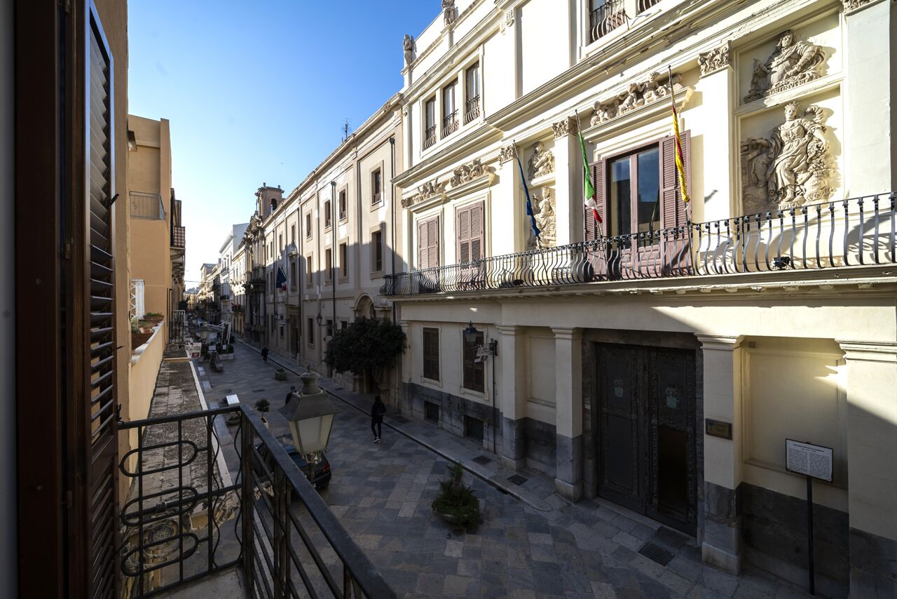 A narrow street with buildings featuring balconies and ornate facades.