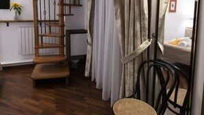 A room with a wooden staircase, a chair, a mirror, and a patterned rug.