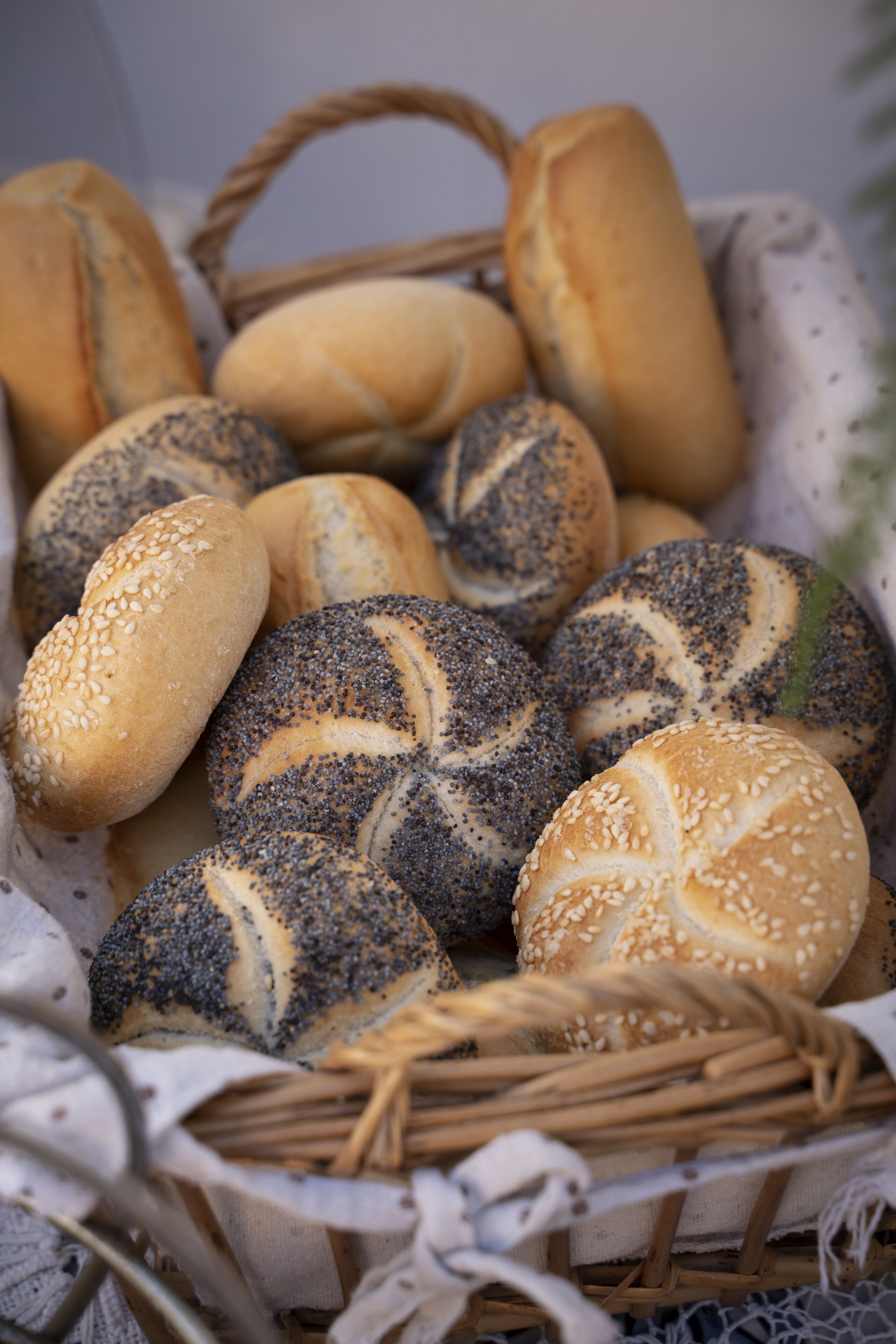 Un cesto con diversi tipi di pane, tra cui panini ai semi di papavero e ai semi di sesamo.