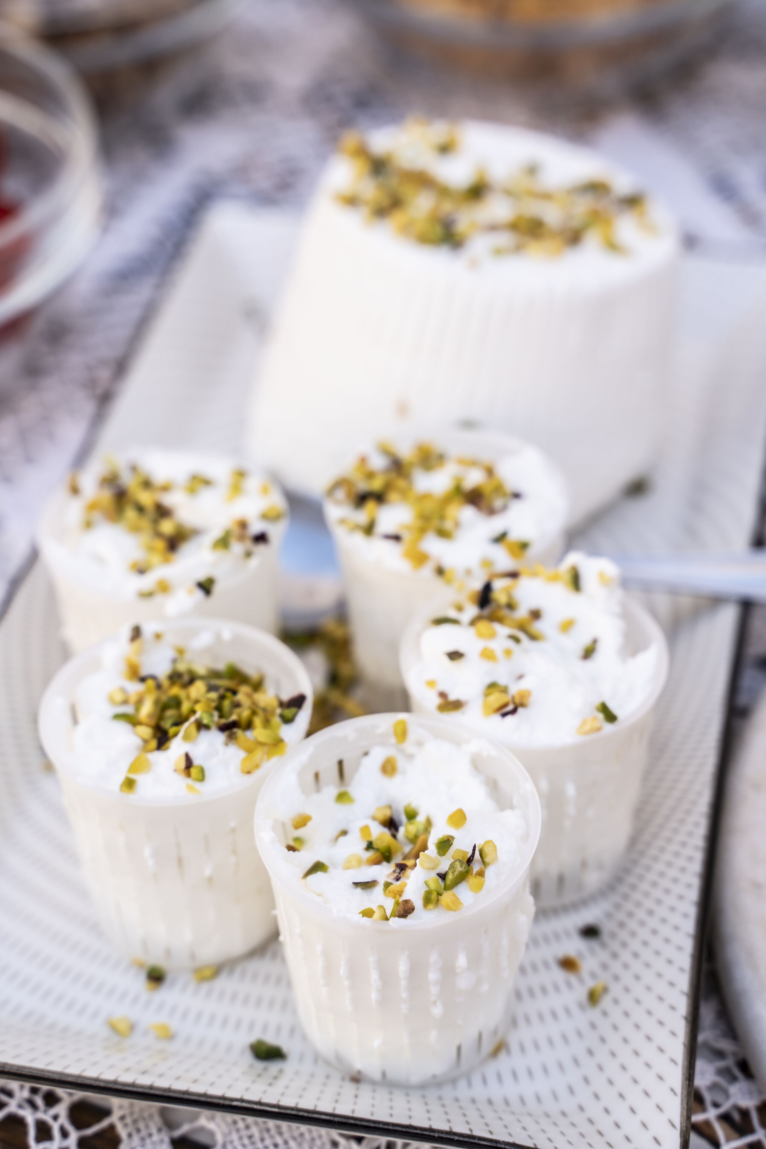 A tray of white dessert cups with pistachio garnish.