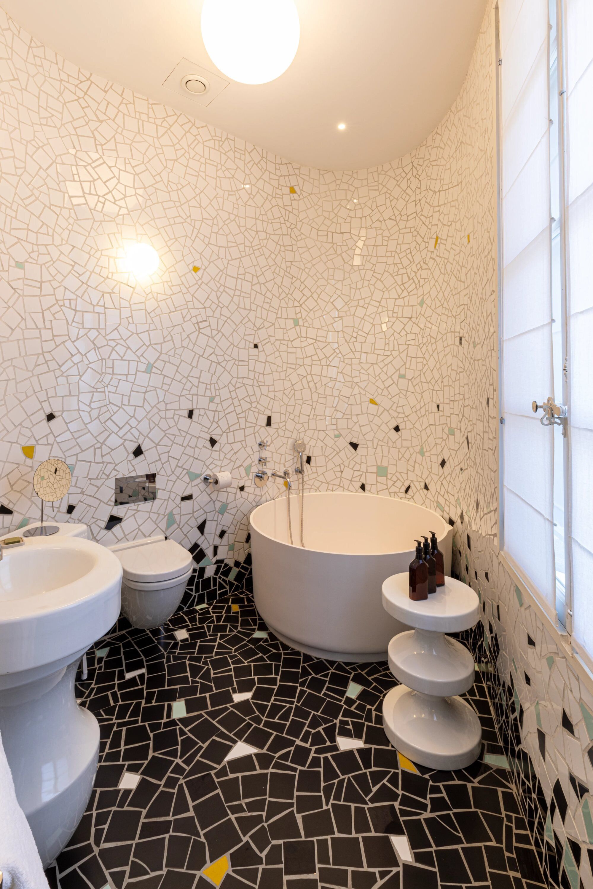 A bathroom with a mosaic floor, a bathtub, a toilet, and a sink.