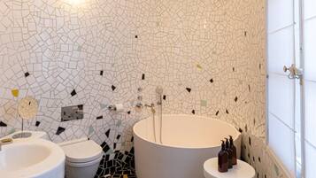 A bathroom with a mosaic floor, a bathtub, a toilet, and a sink.