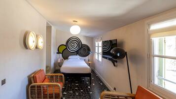 Une chambre d’hôtel avec un lit, deux chaises, une télévision et une fenêtre.