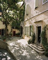 Un patio con pared de piedra, mobiliario exterior y un edificio con letrero del número 18.