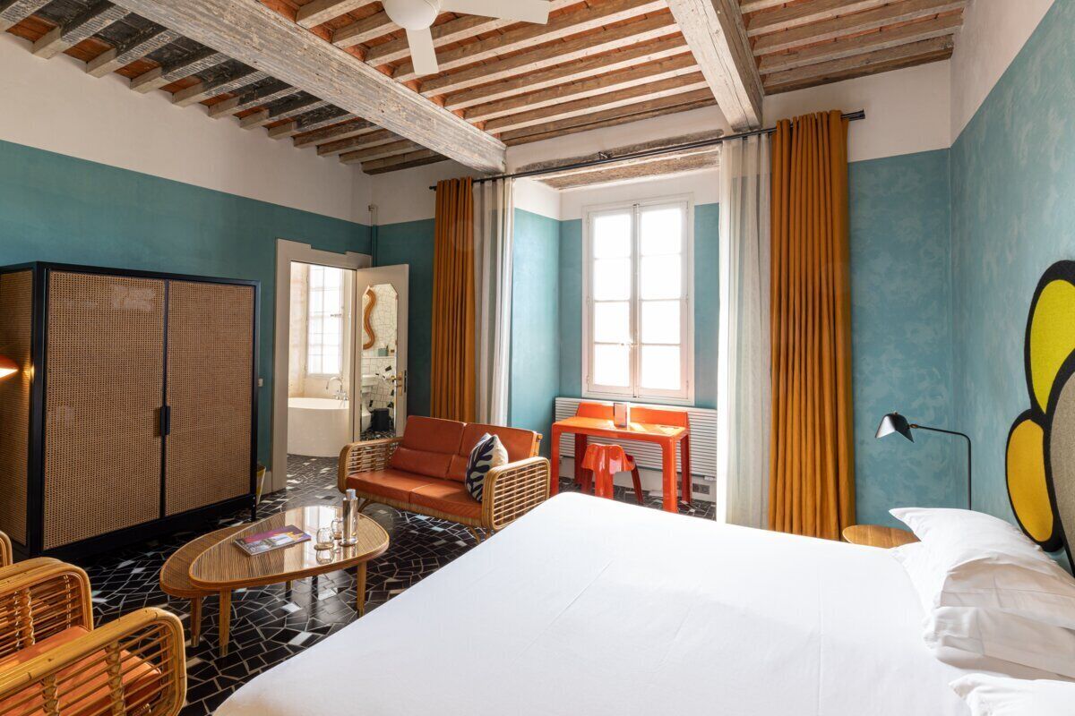 Una habitación de hotel con cama, sofá, mesa y armario.