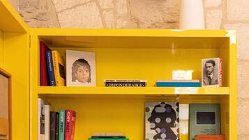 Een gele boekenplank met verschillende boeken en een lamp.
