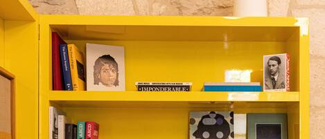 Une bibliothèque jaune contenant divers livres et une lampe.