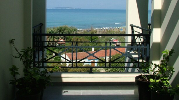 A balcony with a view of the sea and buildings. - Sugar and Almond - Luxury Apartments (Corfu)