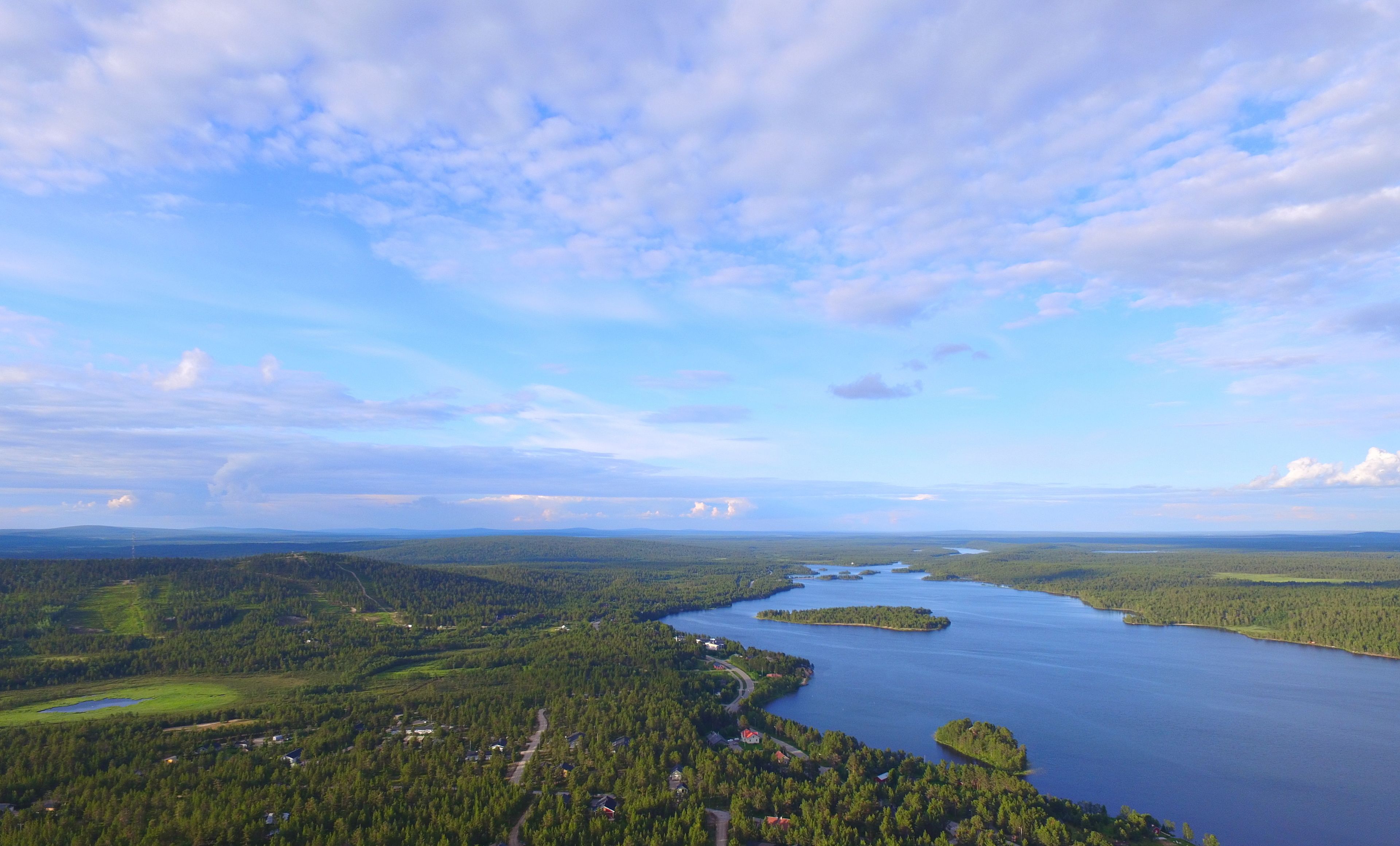 Une vue panoramique d’un lac entouré de forêts denses, sous un ciel dégagé.