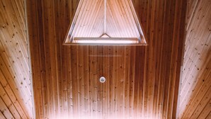 Una habitación con paredes de madera y techo inclinado, con un tragaluz triangular y dos lámparas de noche.