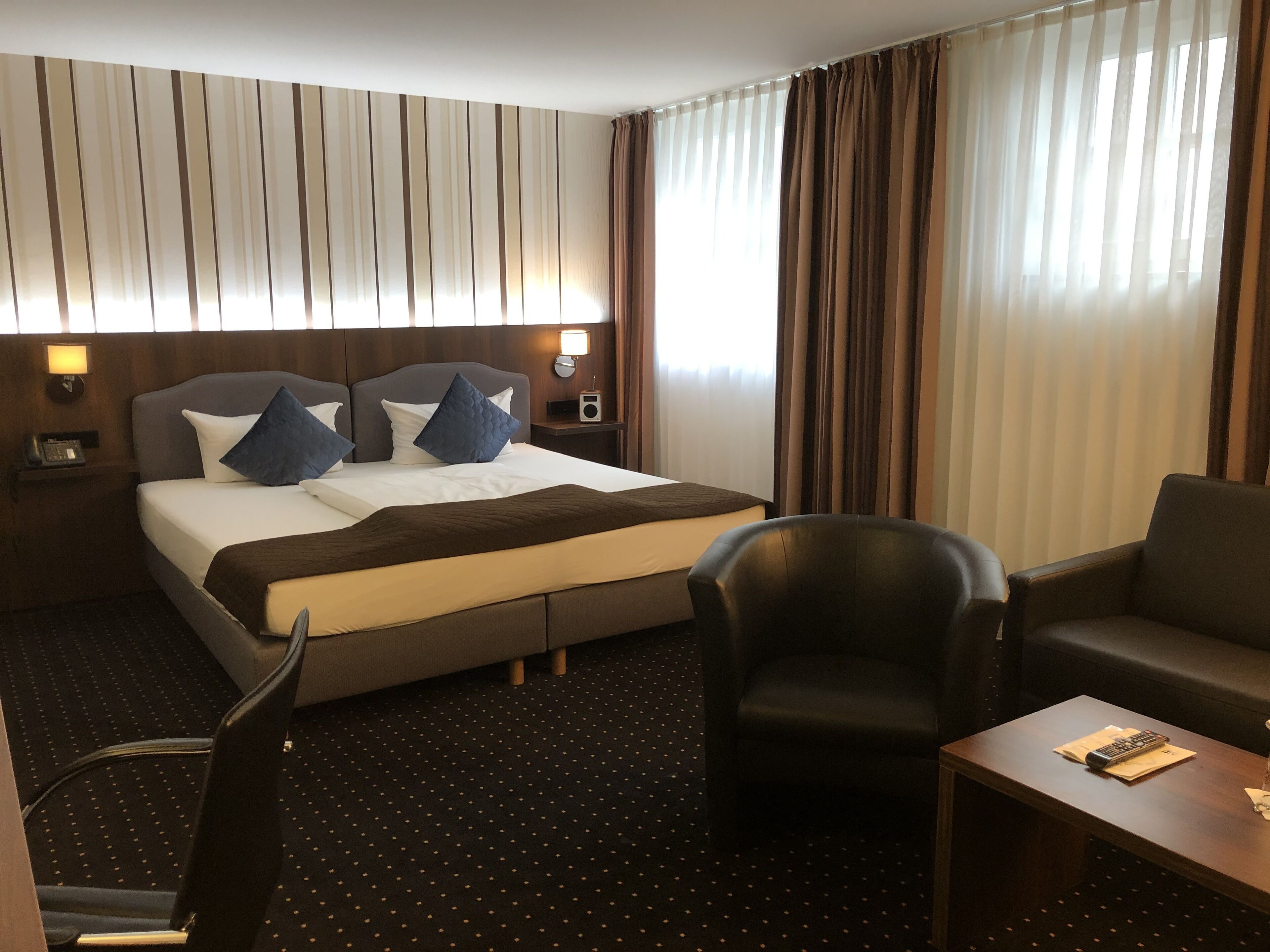 A hotel room with a bed, a desk, a chair, and a TV.