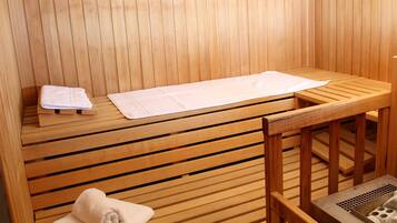 Een houten sauna met banken en een handdoek op de vloer.