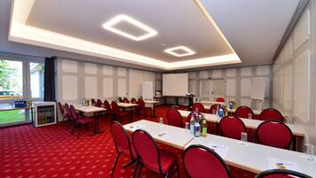 A conference room with multiple tables and chairs, equipped with water bottles and papers.