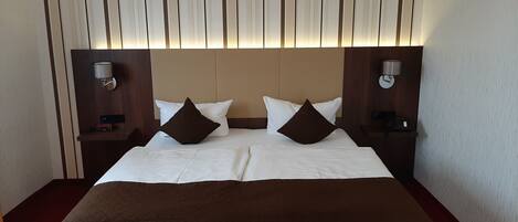 Una habitación de hotel con una cama grande, dos mesitas de noche y un cabecero con rayas verticales.