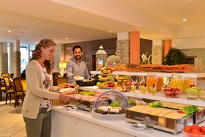 Ein reichhaltiges Buffet mit verschiedenen Speisen und ein Mann, der dahinter steht.