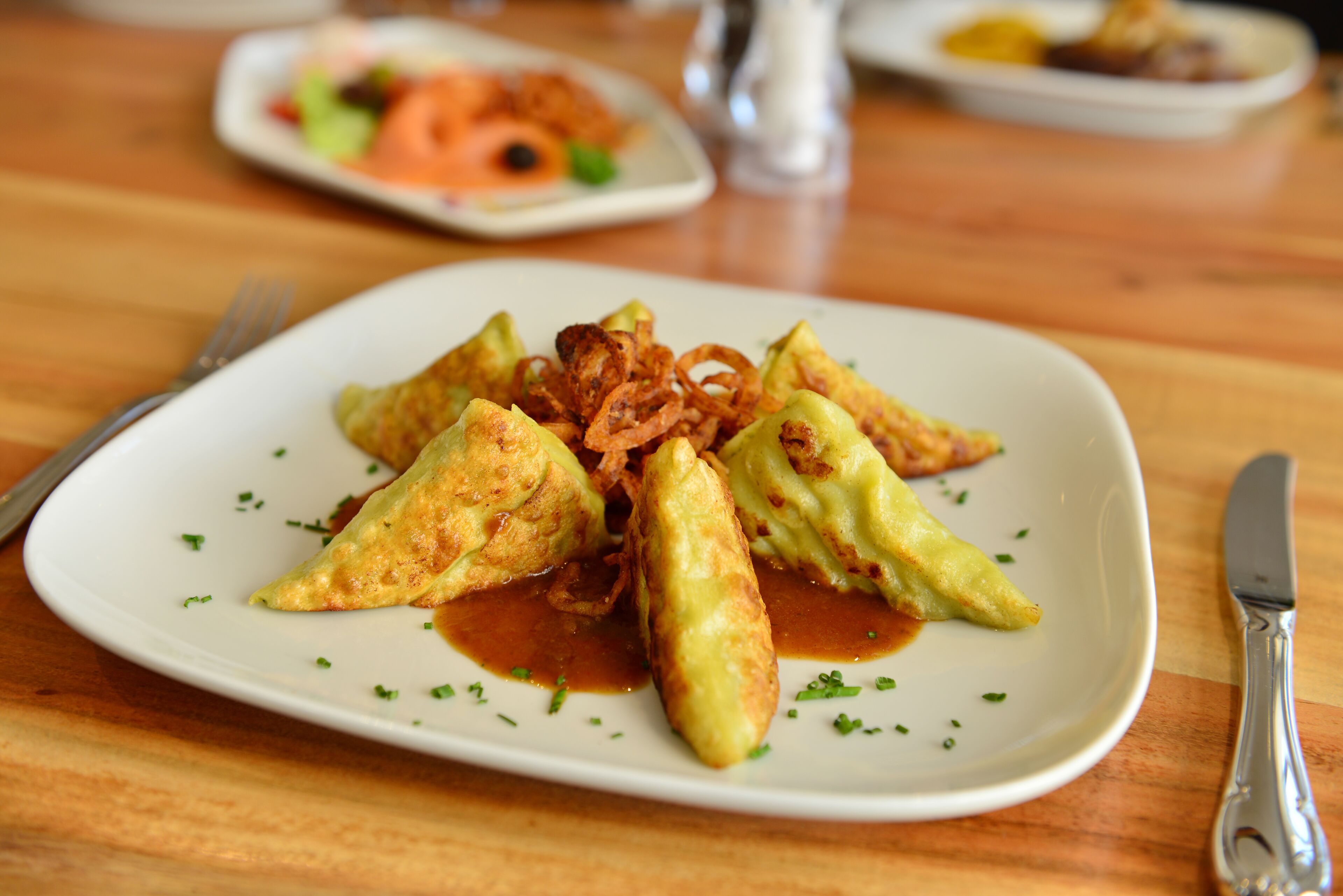 A plate of food with triangular pieces and fried onions on a white plate.