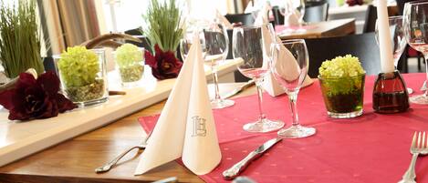 A dining table set with wine glasses, a knife, a fork, and a napkin with a monogram.