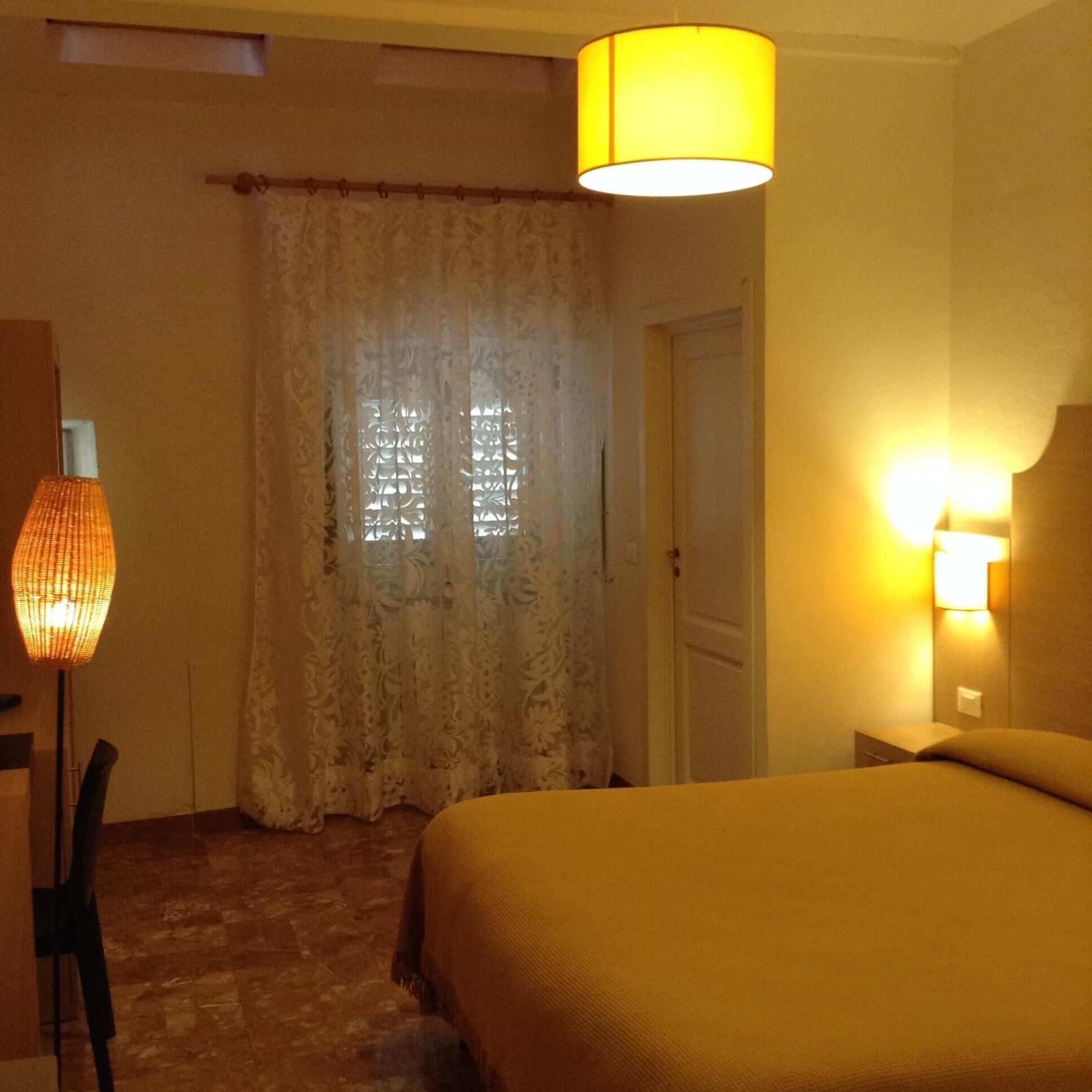 A hotel room with a bed, a lamp, and a door.