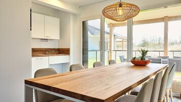 A modern kitchen with white cabinets, a wooden countertop, and a large dining table with chairs.