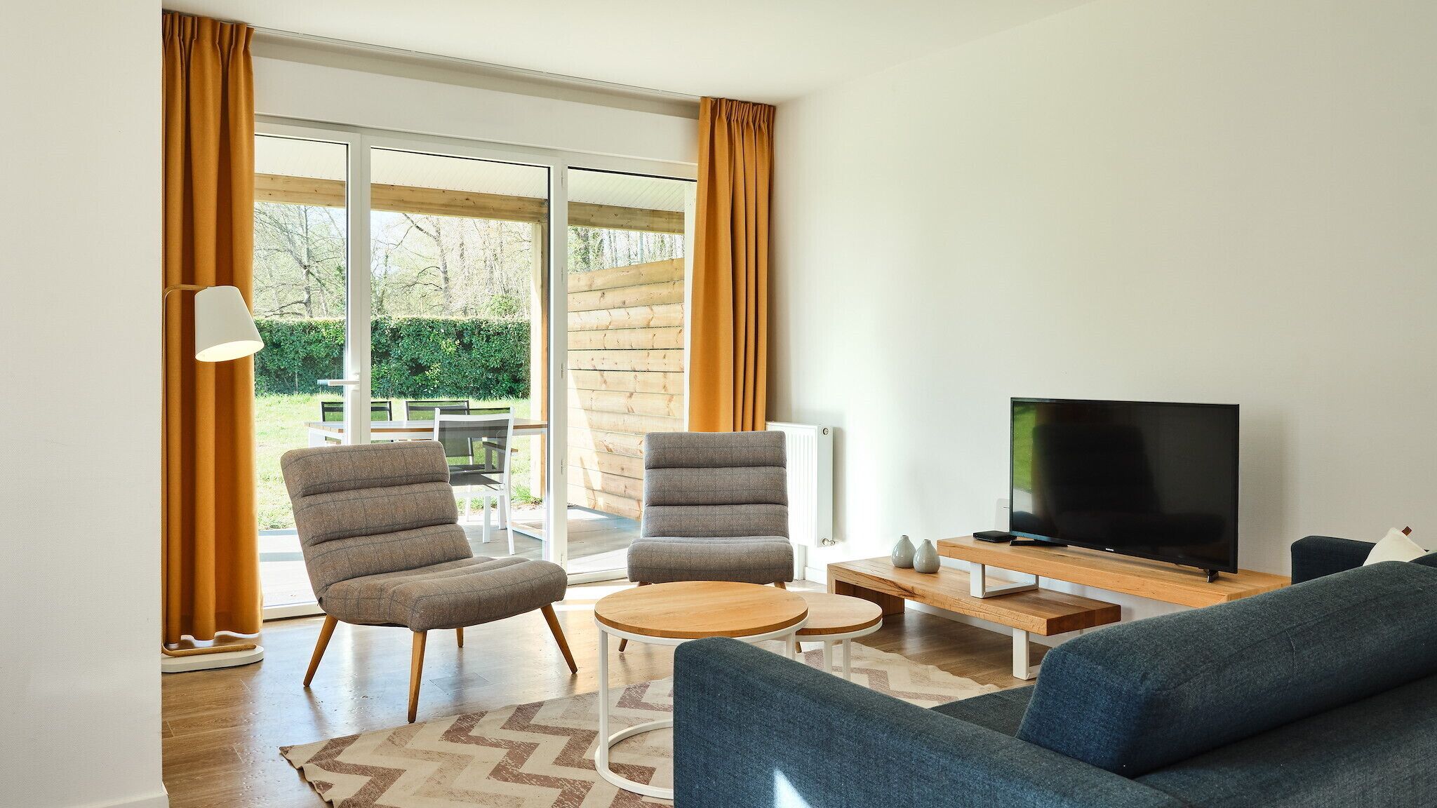 Un salon moderne comprenant un canapé, deux fauteuils, une table basse et un téléviseur.