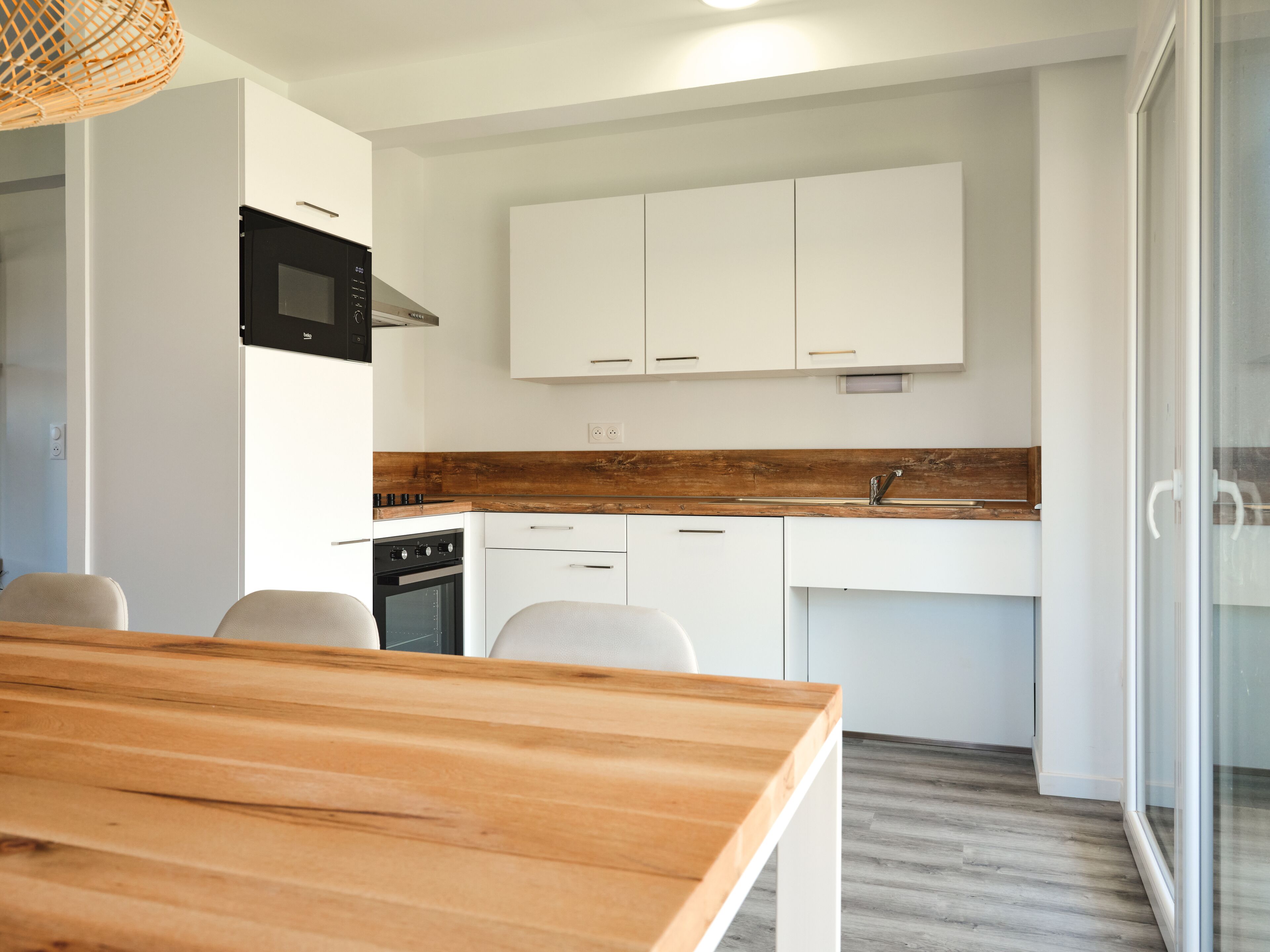 A modern kitchen with white cabinets, a wooden countertop, and a built-in oven.