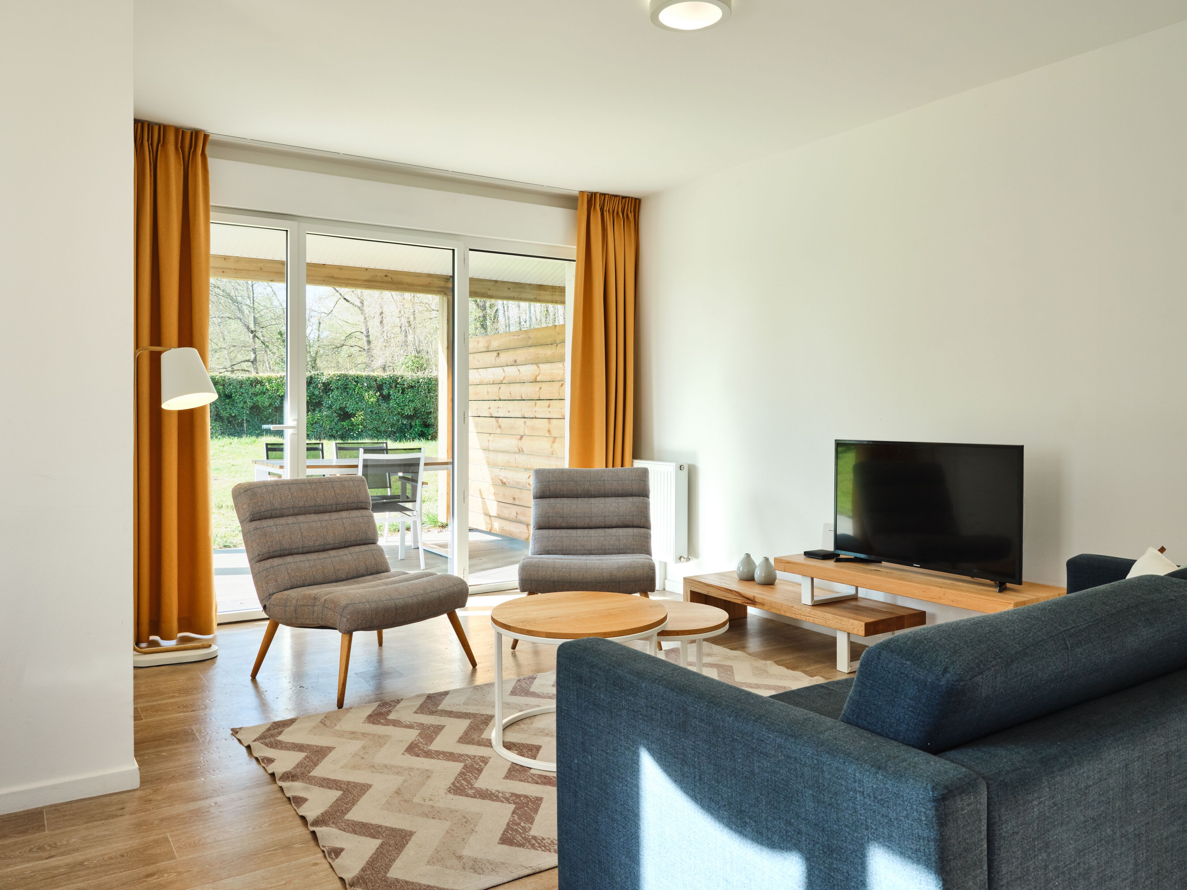 Una sala de estar moderna con un sofá, dos sillones, una mesita de centro y un televisor.
