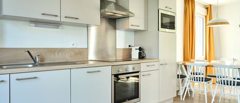 Een moderne keuken met witte kasten, roestvrijstalen apparatuur en een houten aanrecht.