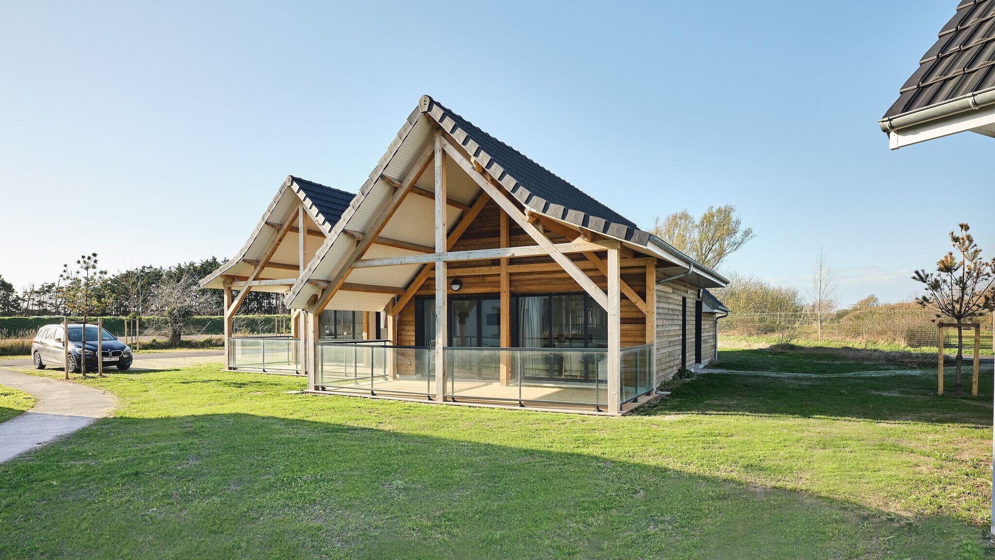 A modern wooden house with a sloped roof and large glass windows.