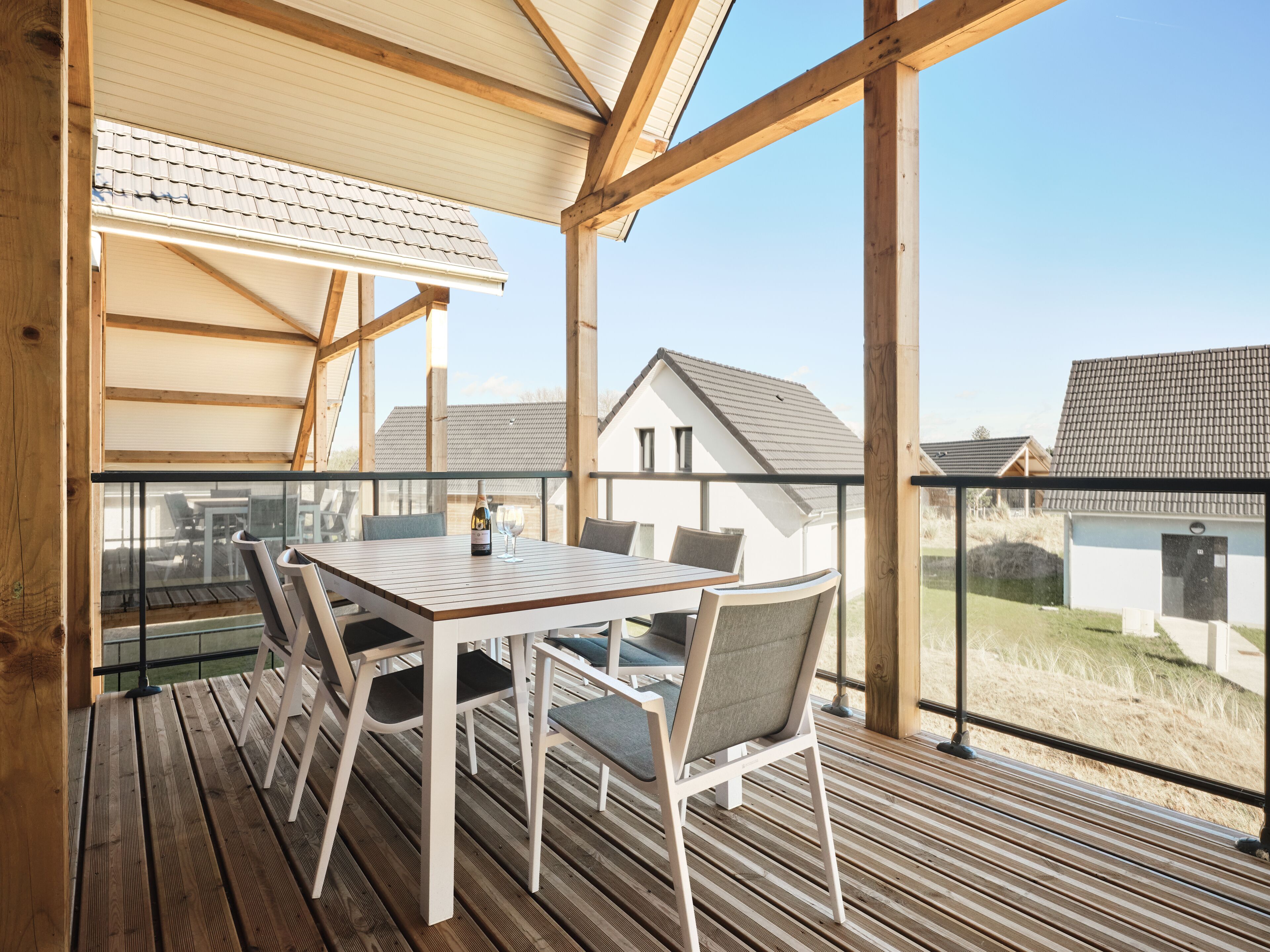 A wooden deck with a table and chairs, overlooking a residential area.