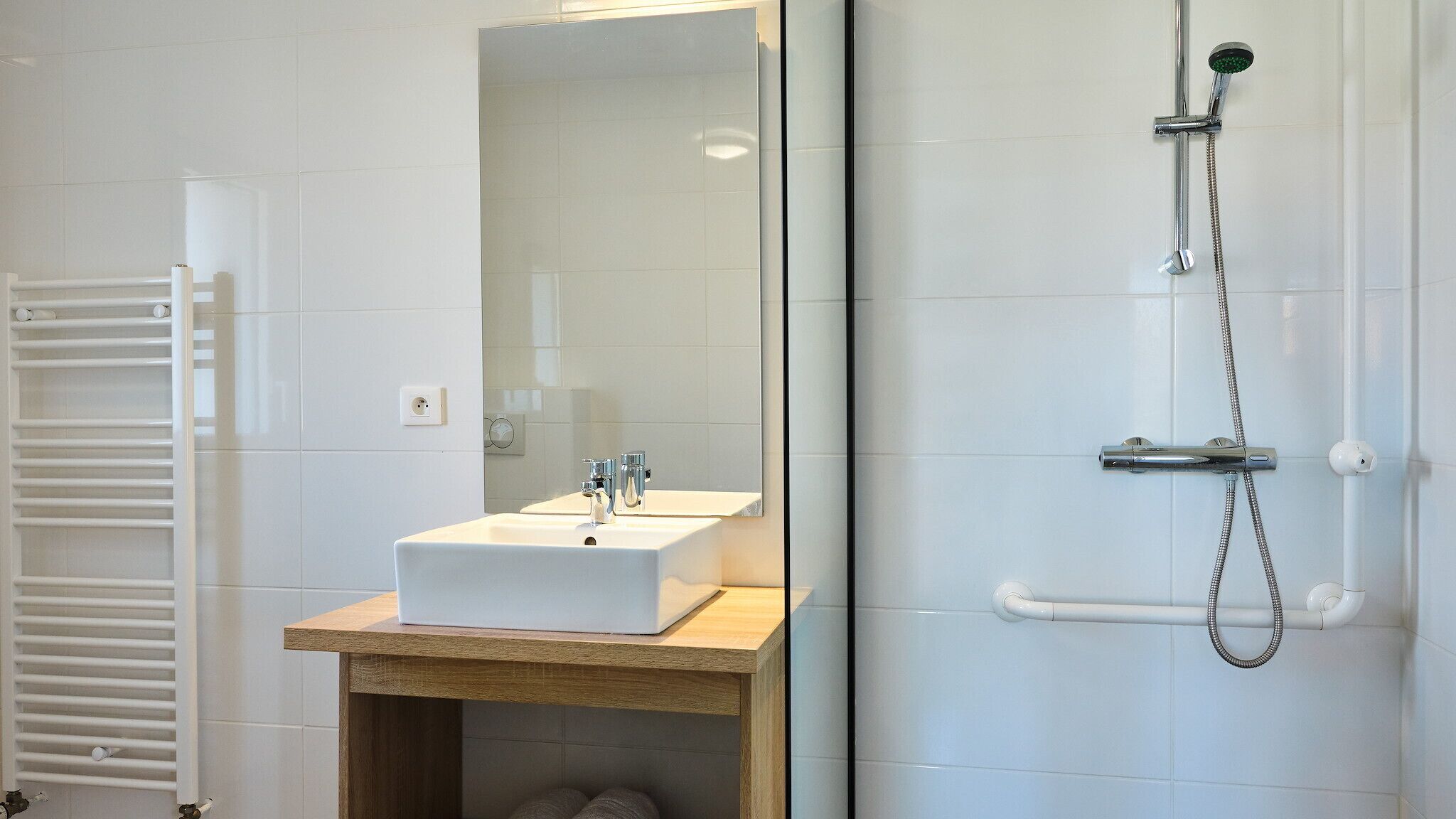 A modern bathroom with a white sink, mirror, and shower.