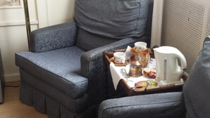 A corner seating area with a table set for tea, a radiator, and floral wallpaper. - Fine Fleur Bed & Breakfast (Bruges)