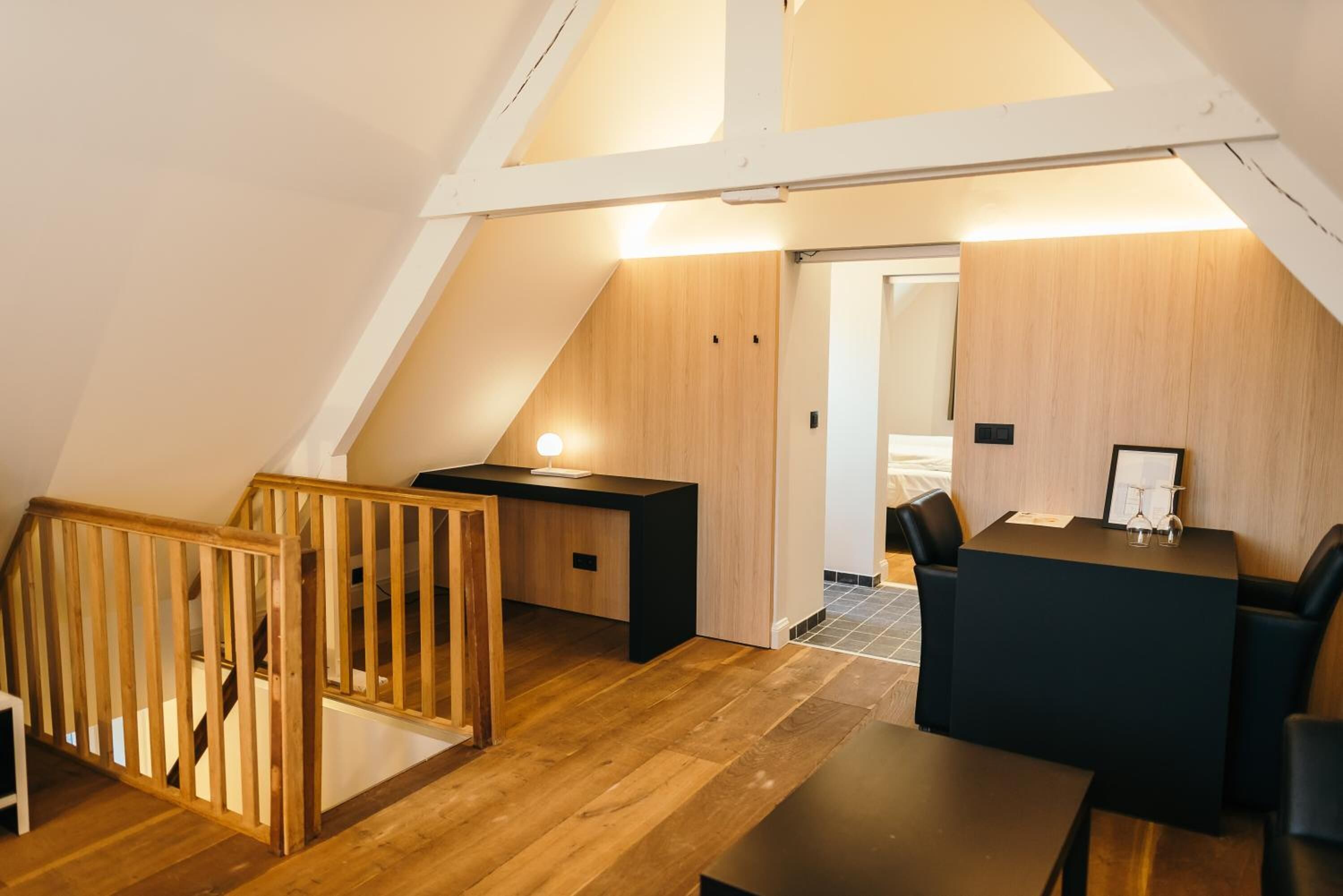 Ein modernes Schlafzimmer im Loft-Stil mit schrägem Dach, Holzboden, einem Schreibtisch und einem Bett.