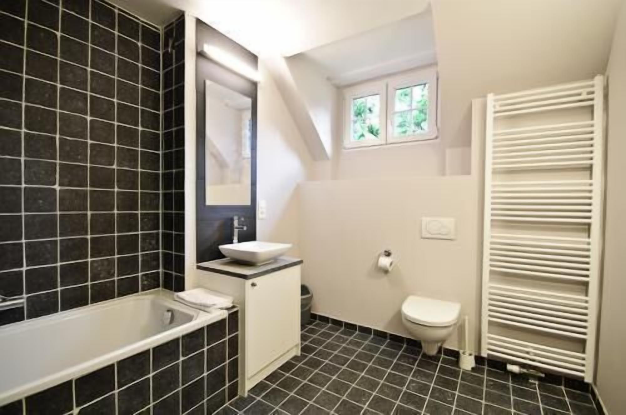A bathroom with a bathtub, a sink, a toilet, and a window.