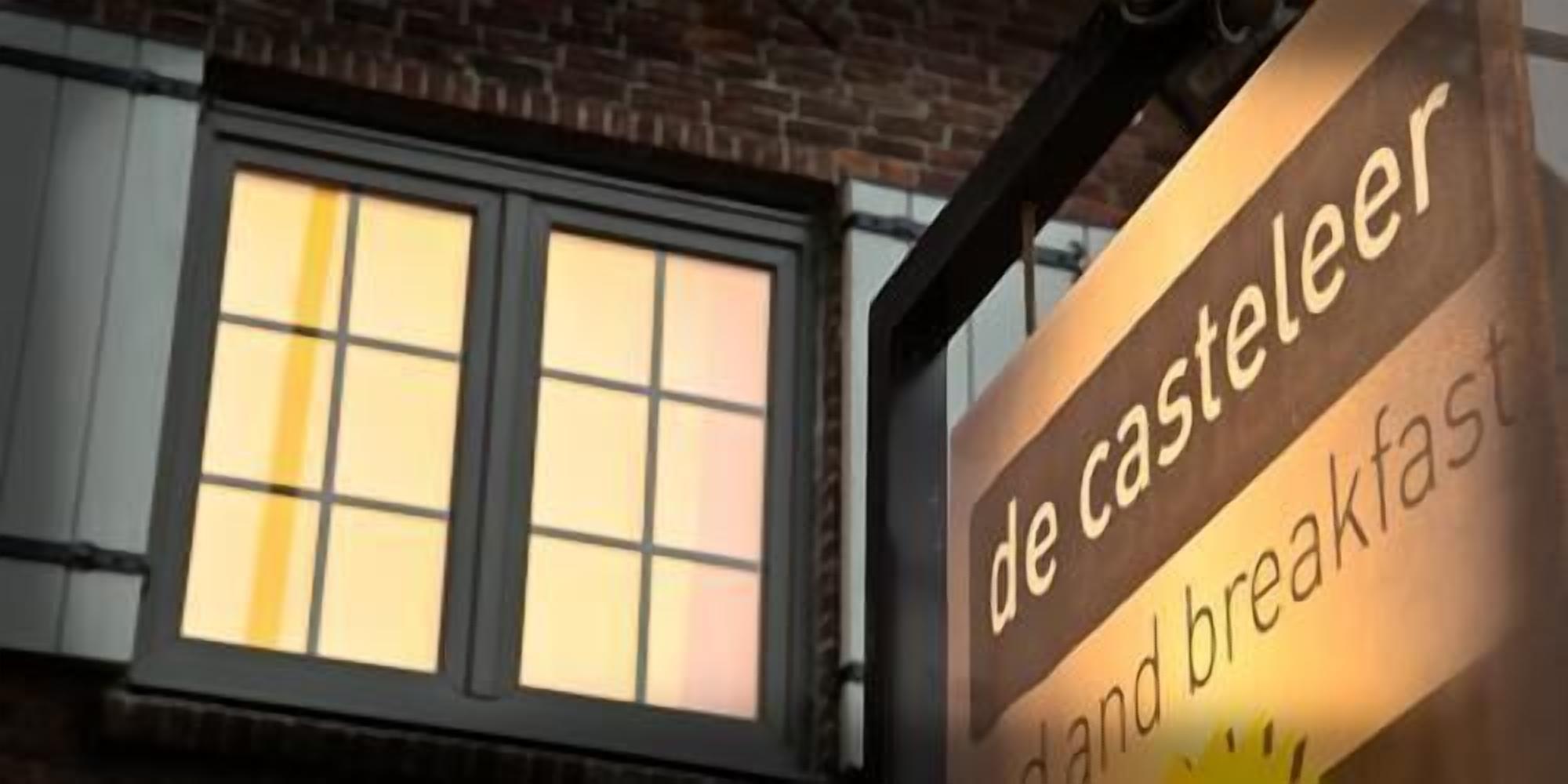 A sign for 'de casteleer hand breakfast' with a window in the background.