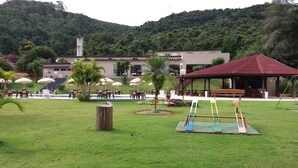 A park area with outdoor seating, a playground, and a building with a red roof. - Hotel Nascentes da Serra (Poços de Caldas)