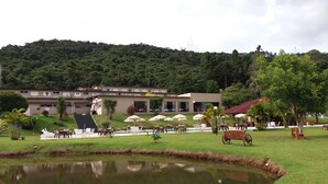 A hotel with a pool, outdoor seating, and a view of a forested hill. - Hotel Nascentes da Serra (Poços de Caldas)
