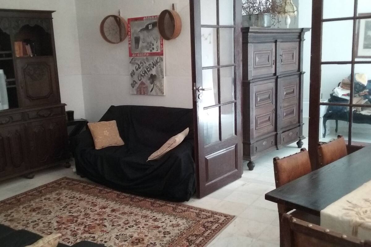 A living room with a black sofa, a patterned rug, a wooden cabinet, and a television.