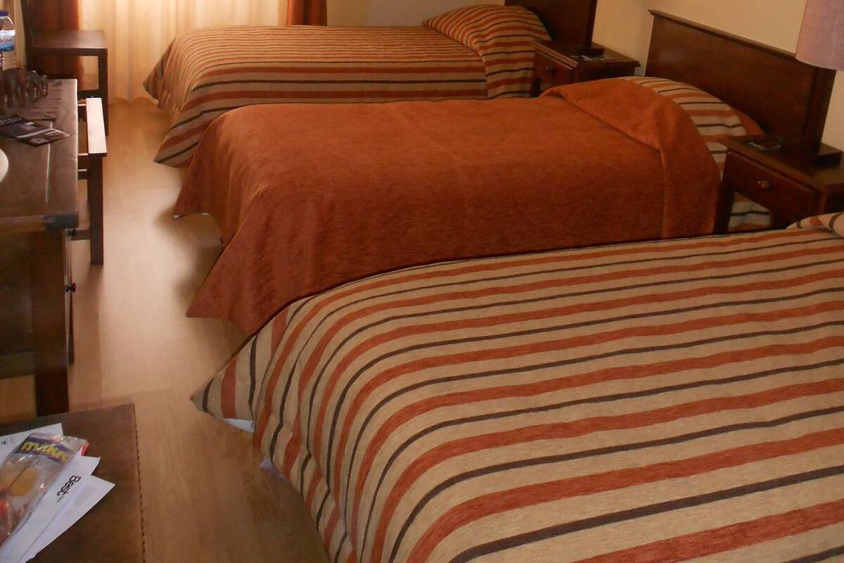 A hotel room with two beds, a desk, and a chair.