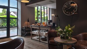 Un café moderno con un amplio ventanal, un reloj y diversas opciones de desayuno en la barra.