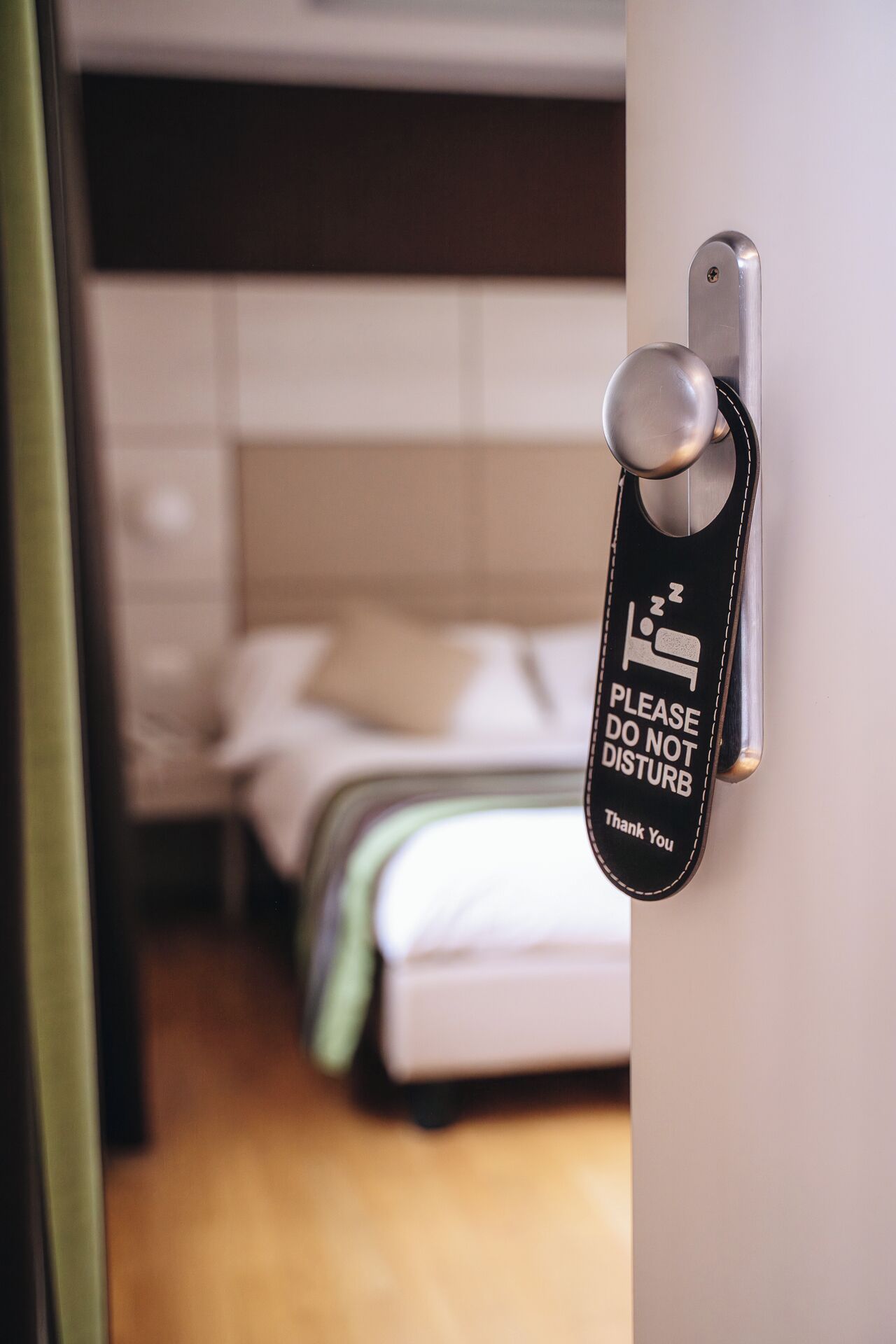 A hotel room door with a sign requesting guests to not disturb.