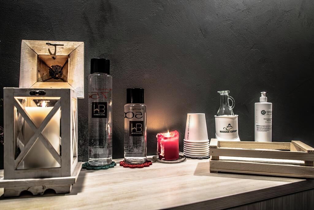 A wooden table with various items including candles, bottles, and a candle holder.
