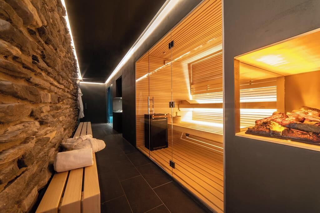 A modern spa area with a stone wall, wooden benches, and a heated stone slab display.