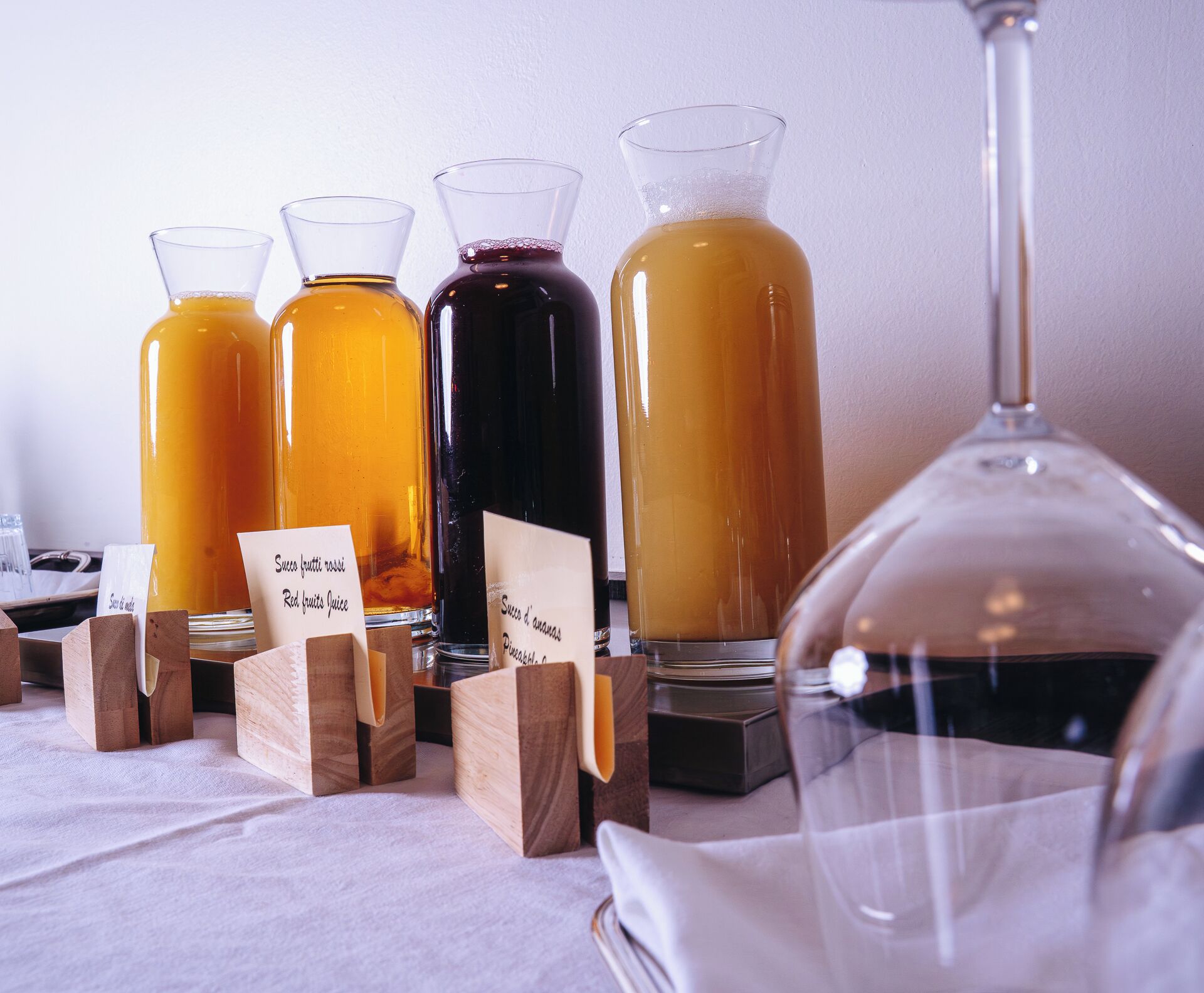 Una mesa con cuatro recipientes de vidrio que contienen bebidas, cada uno identificado con un tipo de bebida diferente.