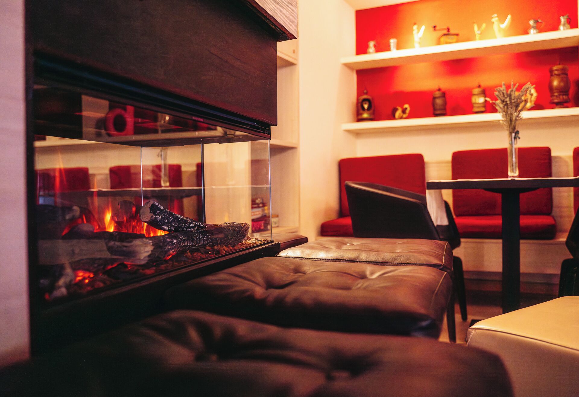 Un acogedor espacio de sala con chimenea, sofá de cuero y sillas rojas.