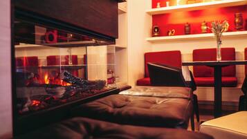 A cozy living area with a fireplace, leather sofa, and red chairs.