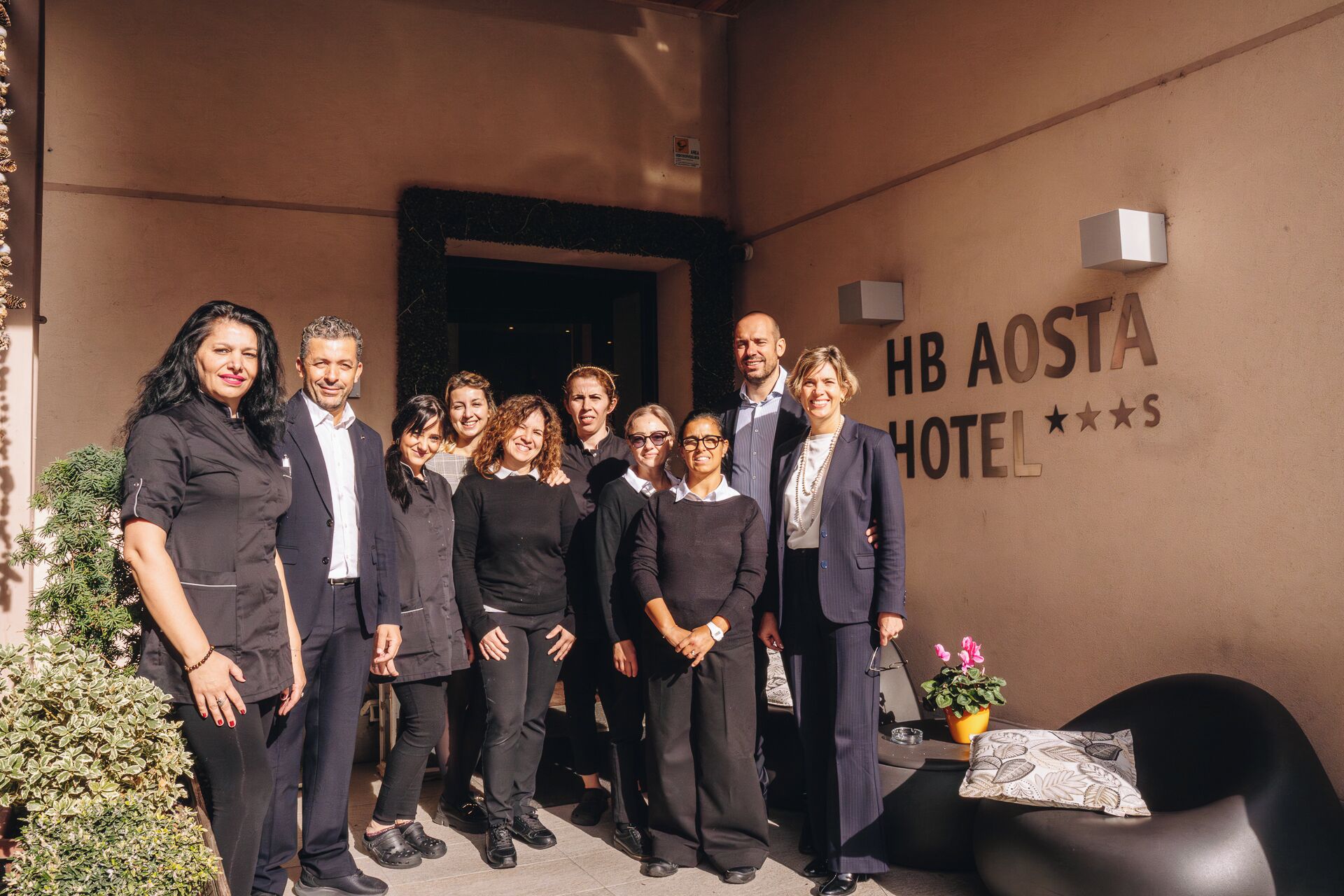 A group of people standing in front of a building with a sign that reads "HB AOSTA HOTEL".