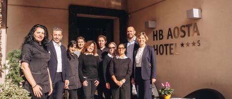 A group of people standing in front of a building with a sign that reads "HB AOSTA HOTEL".