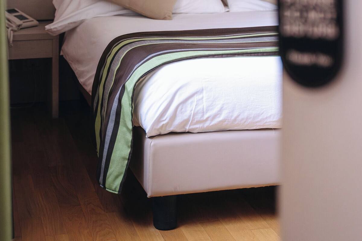 Een hotelkamer met een bed, nachtkastje, lamp en een deur met een RFID-lezer.